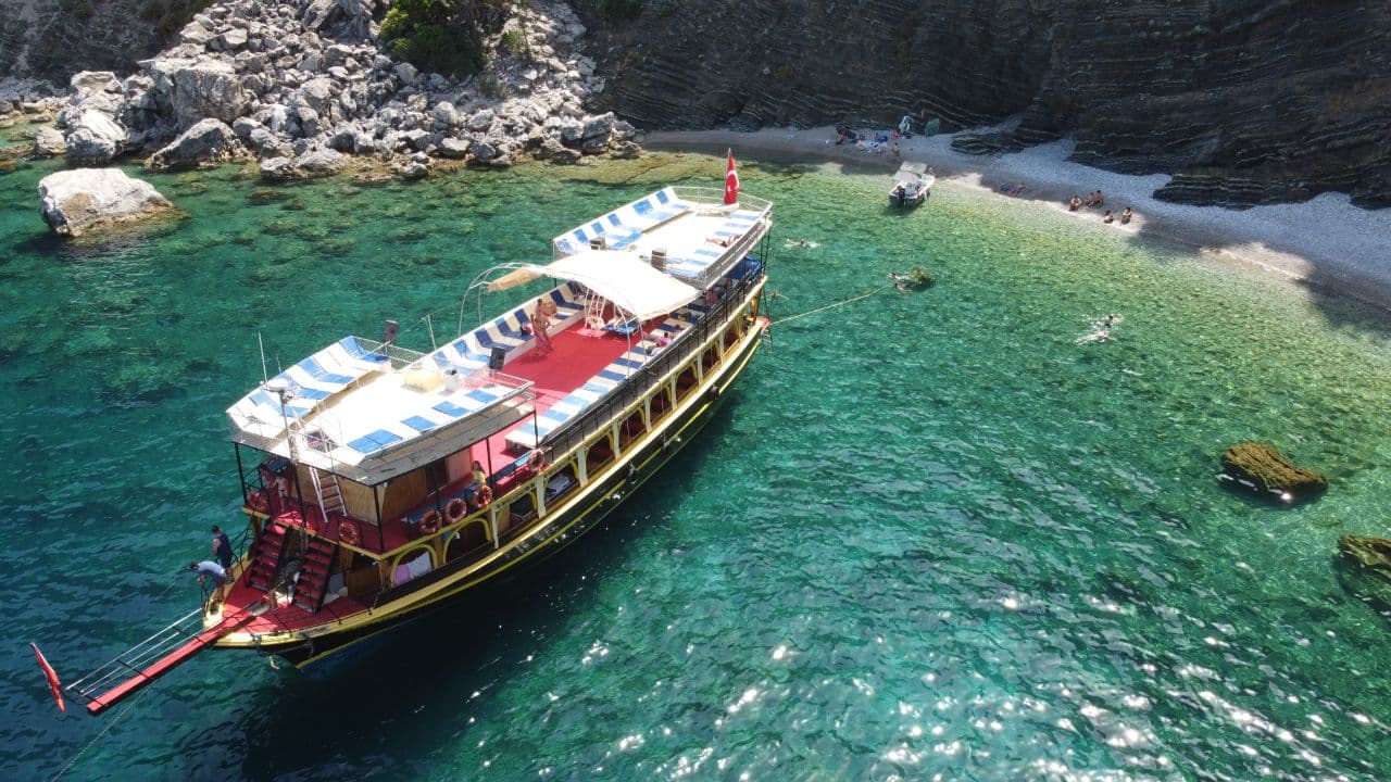 Marmaris boat tour cove stop — gulet moored beside a pebble beach on the Aegean coast